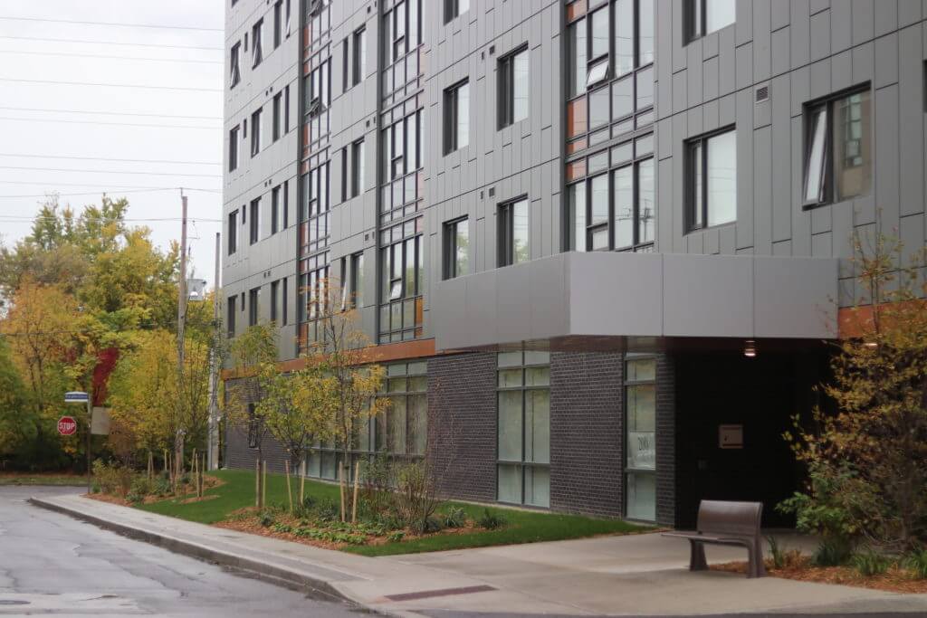 Residential building with trees and bench.