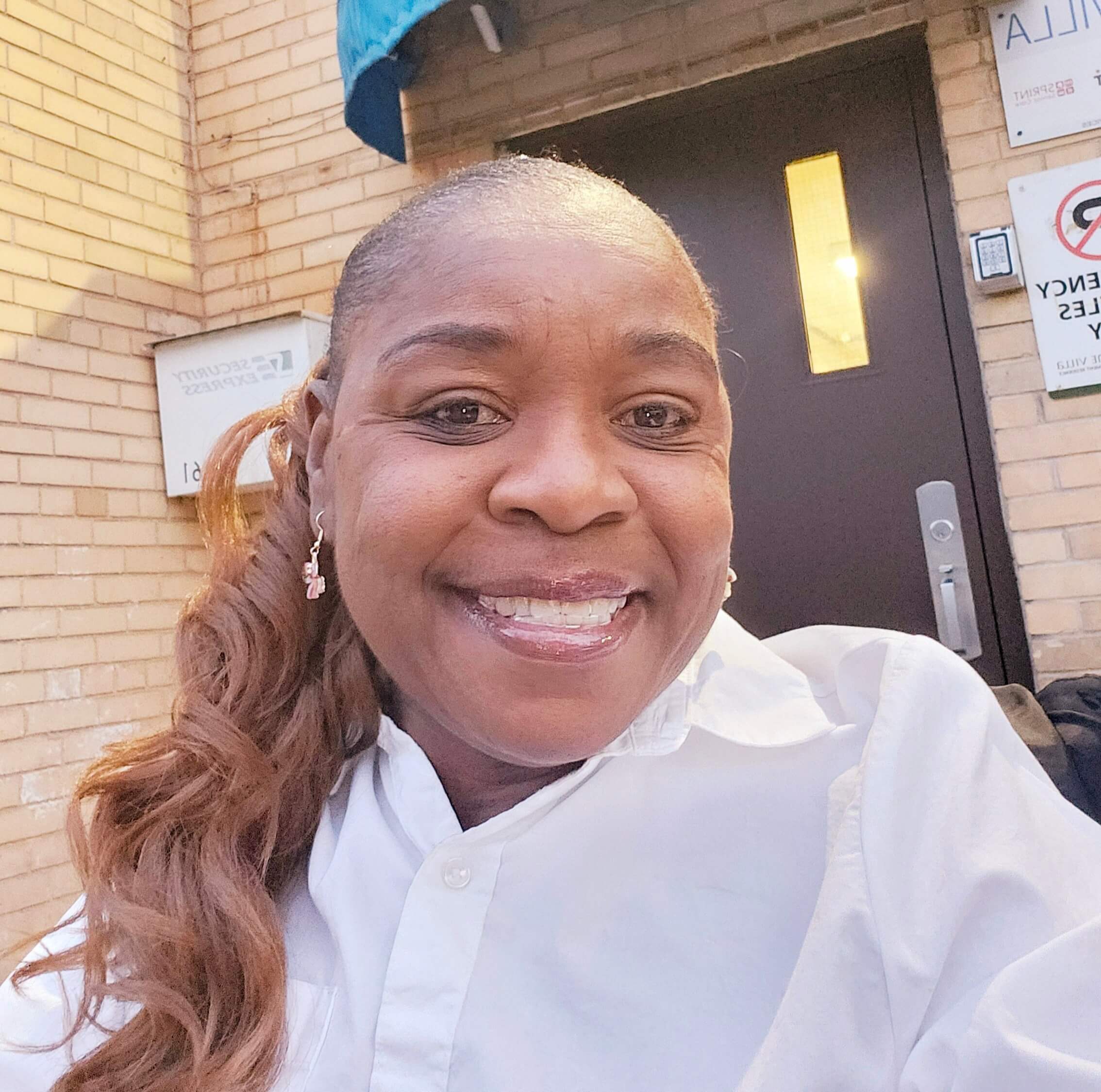 Bellwoods client Leotha Roberts smiles in front of a tan brick building.